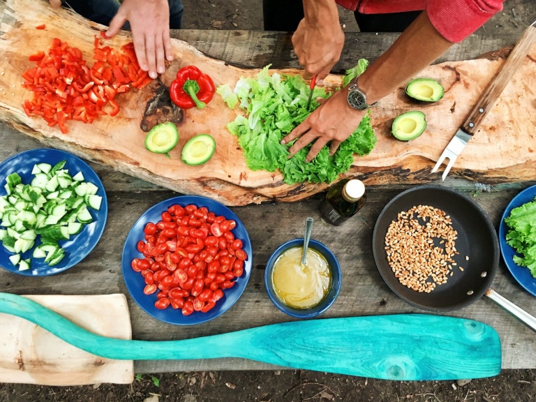 a person creating a meal on a table full of different whole food ingredients